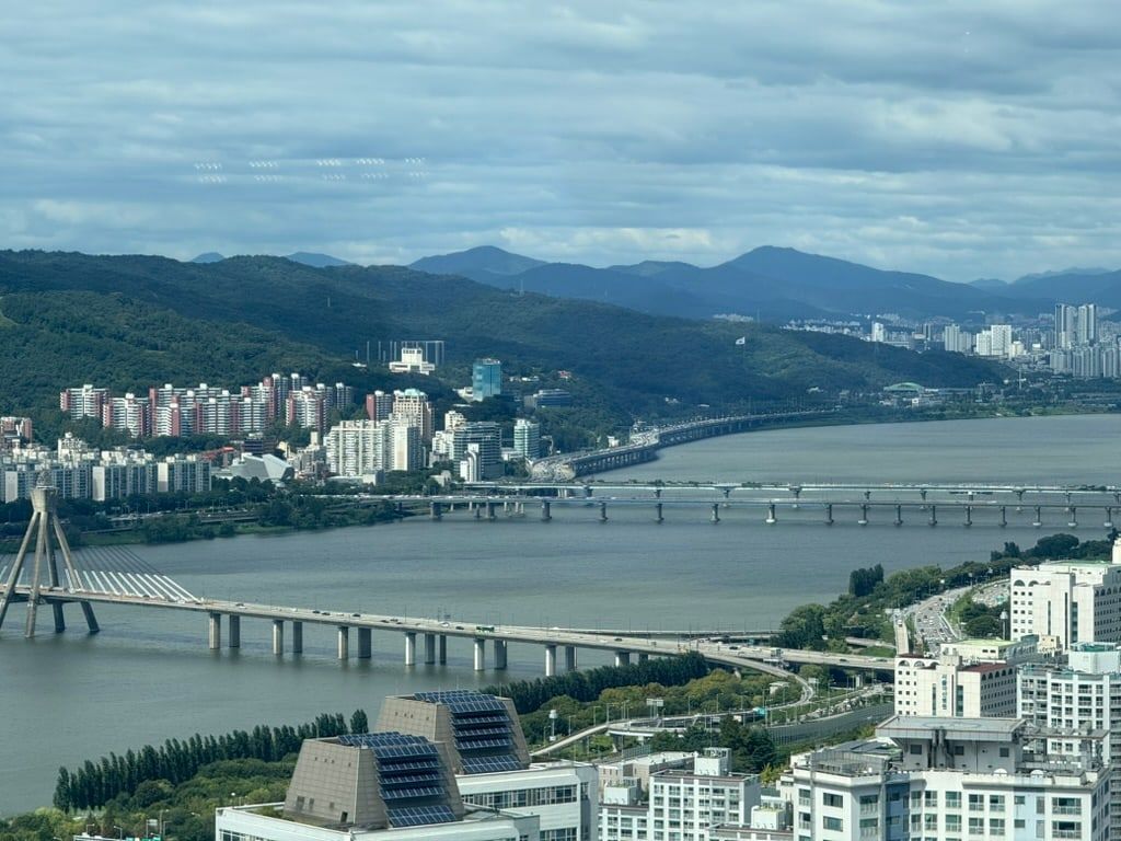 Der Han River in Seoul mit mehreren Brücken, Wohnhochhäusern am Ufer und Bergen im Hintergrund